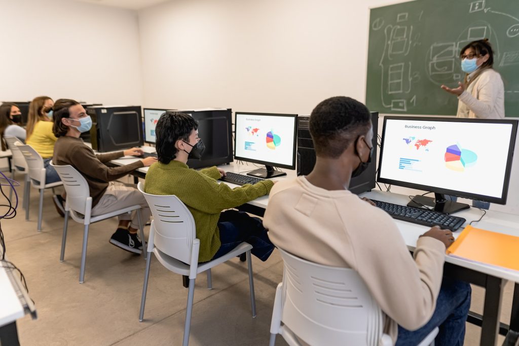 Young students listening a lesson in high school while wearing face mask during corona virus